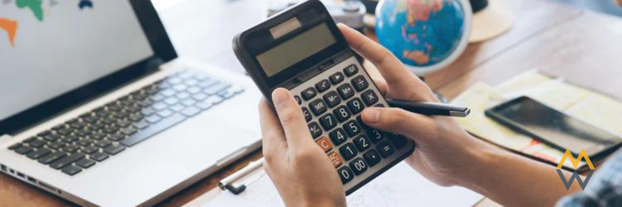 A man holding a calculator at his desk