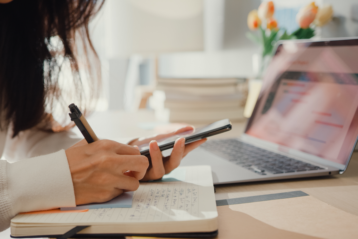 Woman at desk with laptop and mobile phone